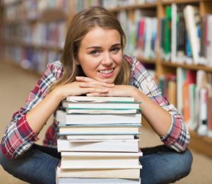 girl with stack of books in library