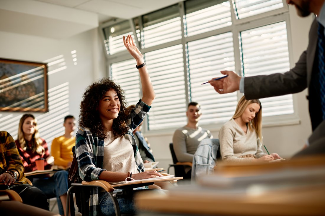 student raising hand in classroom setting