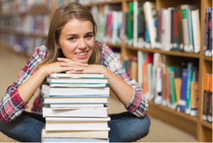 girl in a library with a stack of books